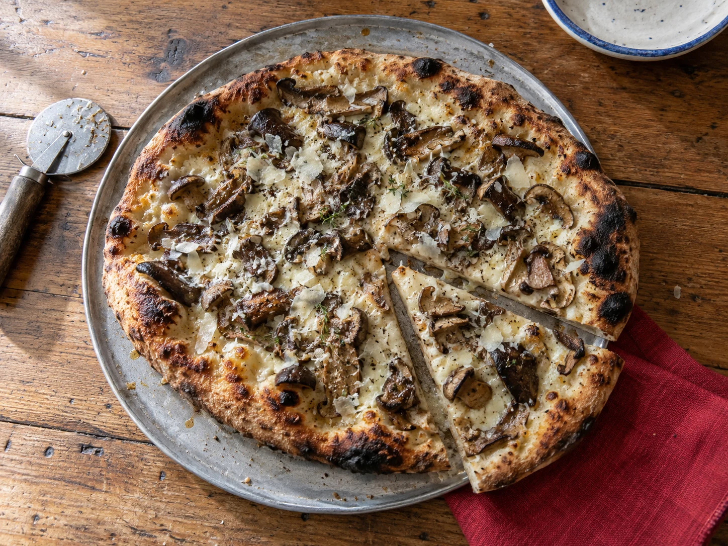 Wild mushroom and pecorino pizza on a worn oak table